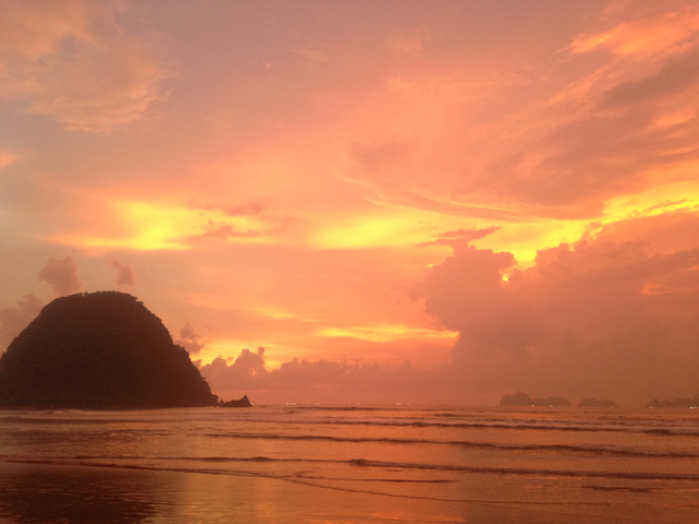Stunning sunset over the ocean with a silhouetted rock.