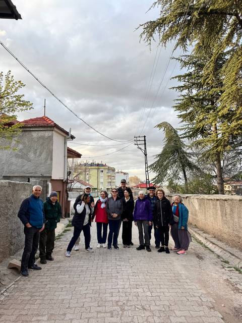 Group of people standing on a street with trees.
