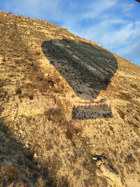 Shadow of a hot air balloon on a rugged terrain.
