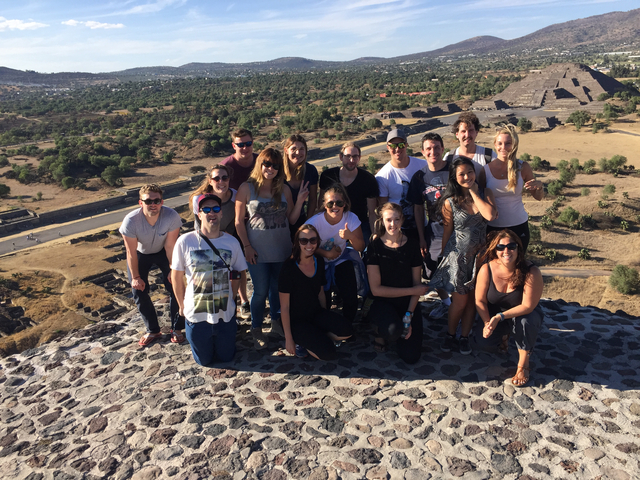 Group standing atop a stone structure with a scenic view.