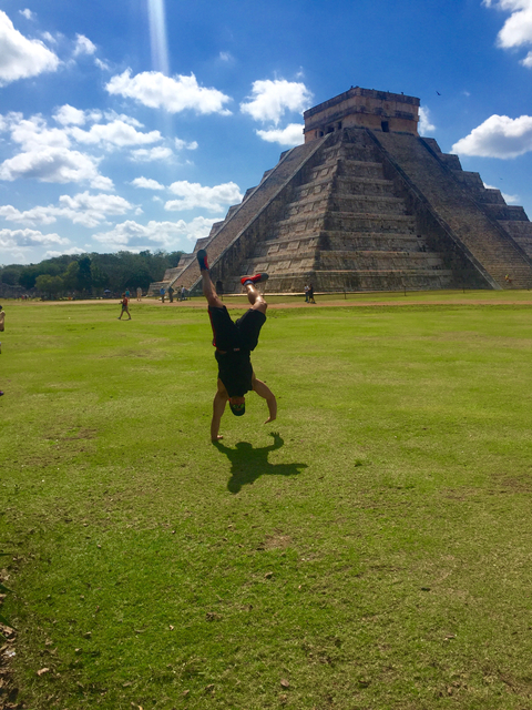 Person doing a handstand in front of a pyramid.