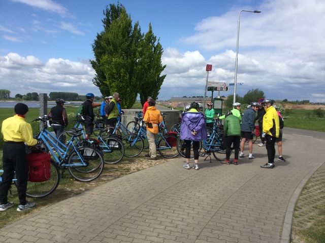 Cyclists gathered on a path with their bicycles.