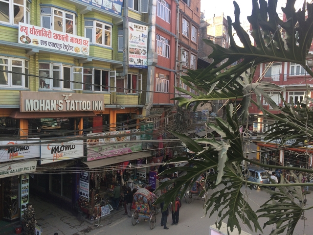 Busy street market scene with a view of shop signs and cables.