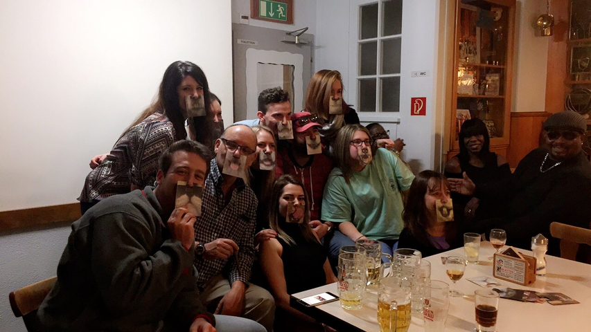       Group of people making faces with beer glasses in a pub.
  