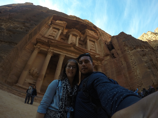 A couple taking a selfie in front of a monumental rock facade.