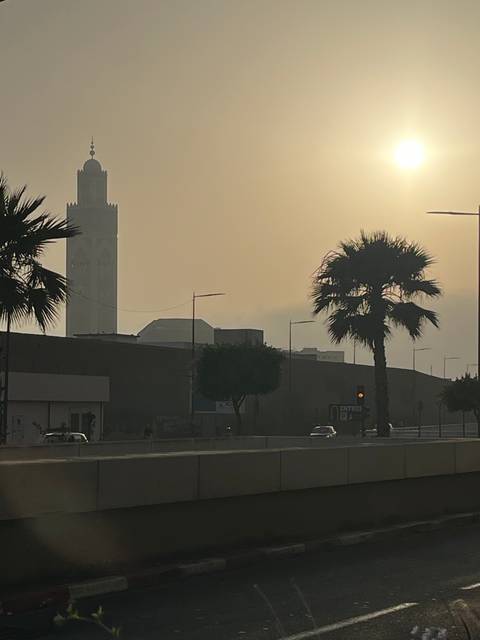 Silhouette of a building with a tall minaret against a hazy sky.