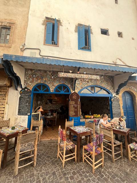 Outdoor café with blue decorative tiles and patrons seated at tables.