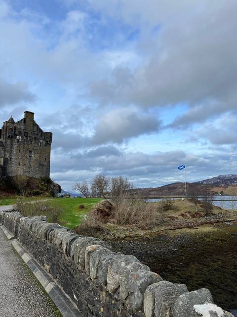 Stone wall with a Scottish flag in a rural area.