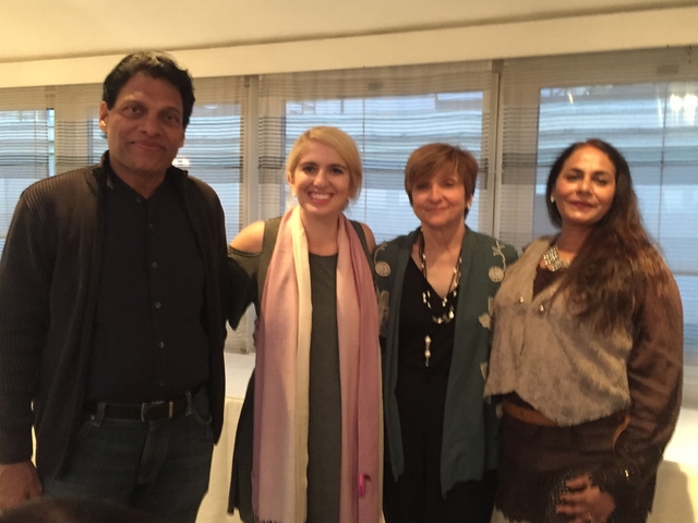 Four people posing indoors with blurred background.