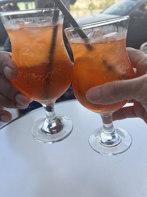 Two glasses with orange drinks being held.