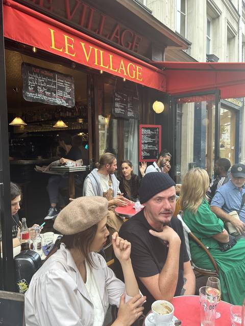 People sitting outside a cafe with a red awning.