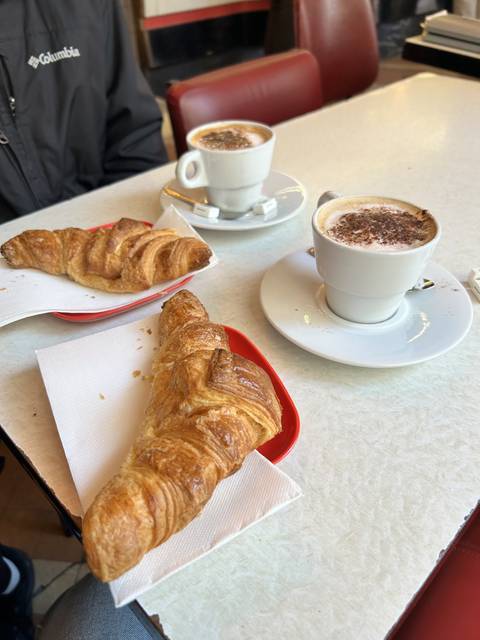       Crossaints and cappuccino on a table.
  
