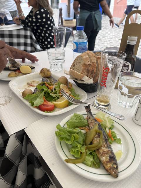 Table with bread, salad, and grilled fish.