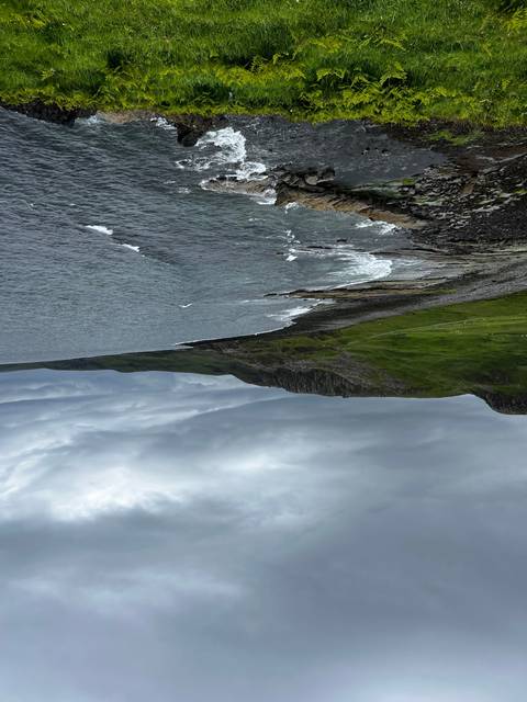       River and rocky cliffs with a cloudy sky, evoking a sense of wilderness.
  