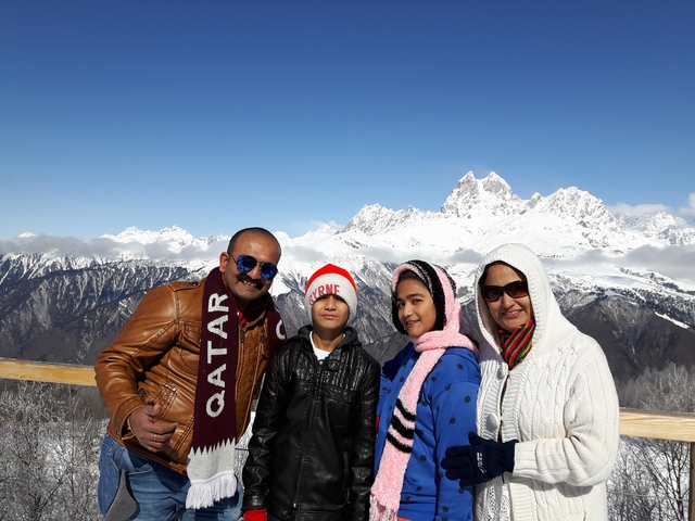 Family posing with snow-covered mountains in the background.