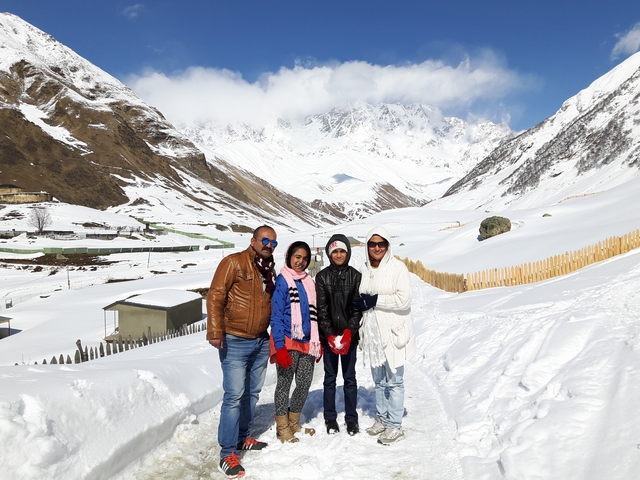 Family posing on a snowy path with mountainous terrain.