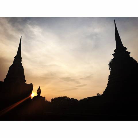       Silhouettes of temple spires against a sunset sky.
  