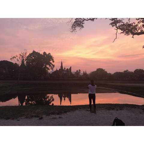       Silhouette of a person enjoying the sunset view with a reflection in water.
  