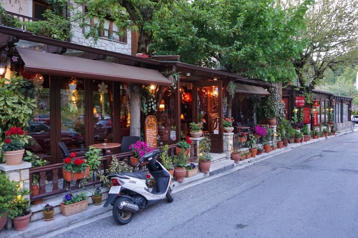 A charming cafe decorated with plants and flowers on a street.