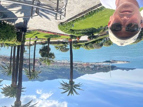       Person wearing a hat with an upside-down view of a coastal garden.
  