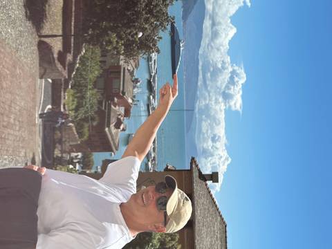 Person pointing at a scenic view of a coastal town and sea.