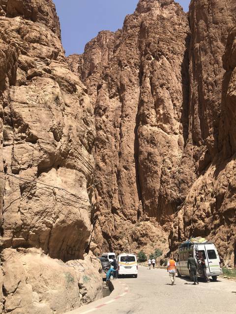       Narrow canyon with high rock walls and tourists walking.
  