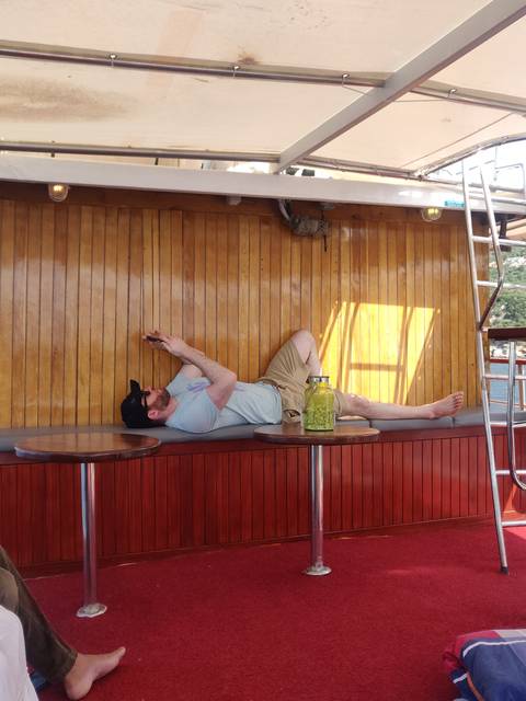 Person relaxing on a boat with wood paneling.