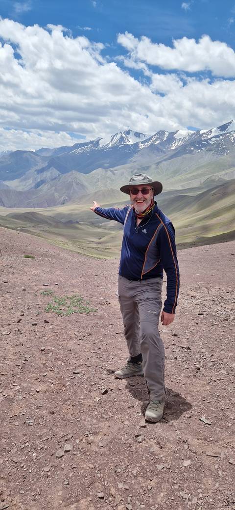 Person posing on a slope with mountains in the background.