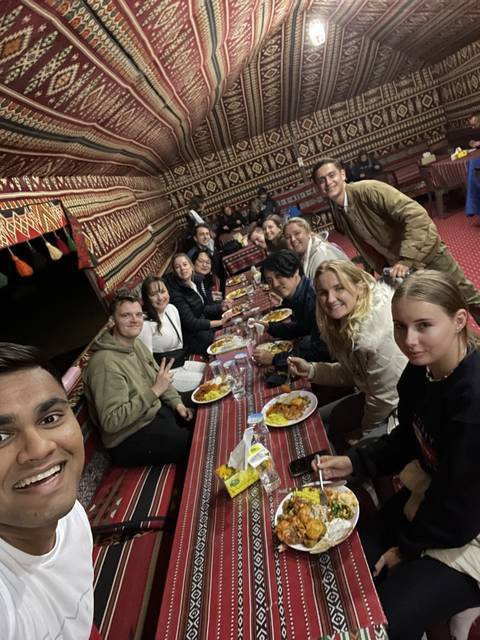 Large group enjoying a traditional meal in a vibrant carpeted interior.