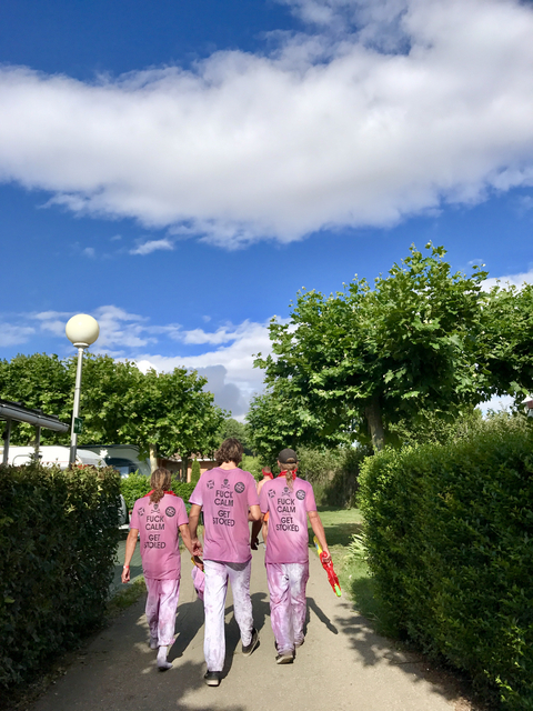       Three people wearing pink shirts walking on a tree-lined path.
  