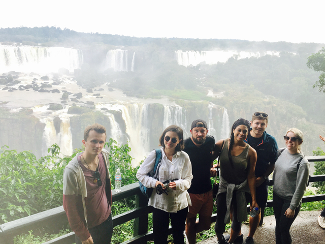 People posing with the breathtaking view of Iguazu Falls behind them.