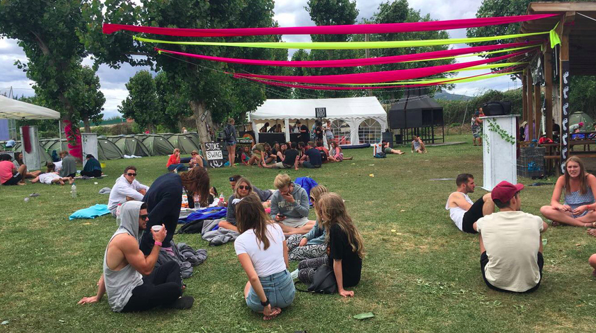       People relaxing at an outdoor festival with colorful decorations.
  