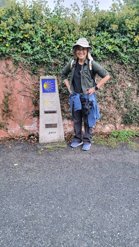Person with a Camino de Santiago marker and scallop shell symbol.