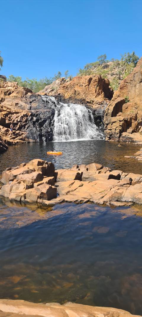       A waterfall over rocky cliffs with a calm pool below.
  