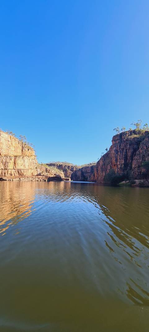 A river flowing between high cliff walls under a clear blue sky.