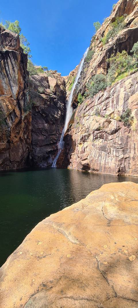 A waterfall flowing into a rocky pool surrounded by cliffs.