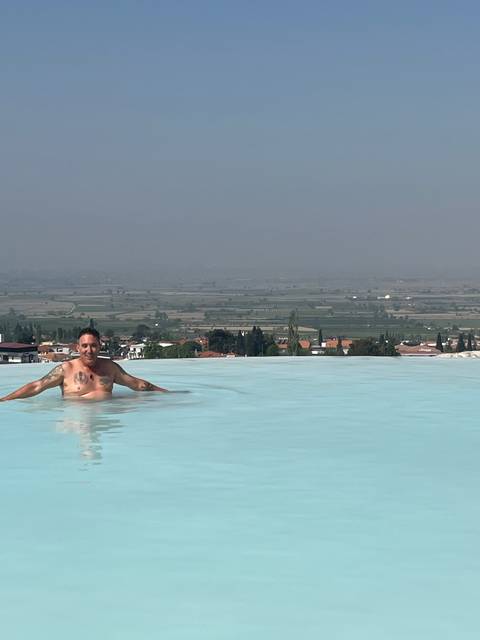       Person swimming in an infinity pool overlooking a landscape.
  