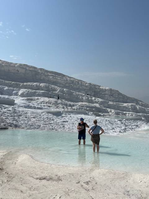       People walking on a white terrace formation.
  