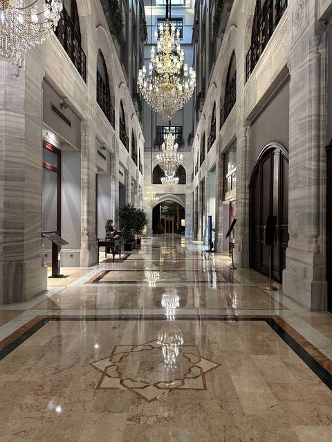 Luxurious hotel interior with chandeliers and marble floors.
