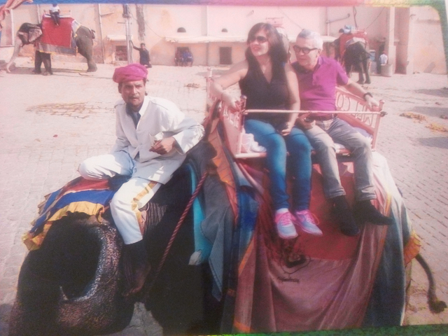       Two people riding an elephant with a guide.
  