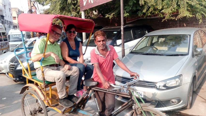       People sitting in a rickshaw on a busy street.
  