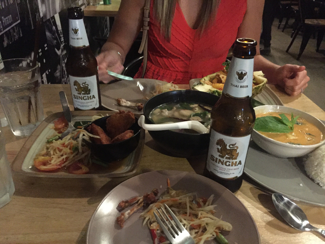 Table filled with Thai food and beverages including Singha beer.