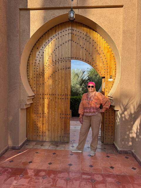 Woman standing in front of an ornate wooden door.