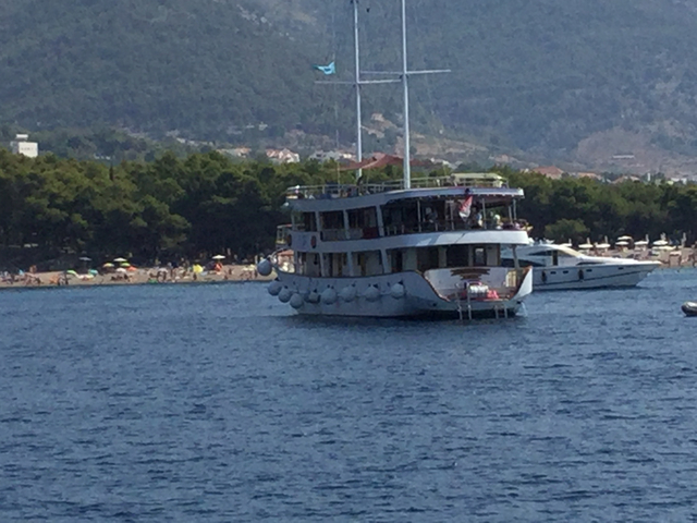 A passenger boat in the sea with hills in the background.