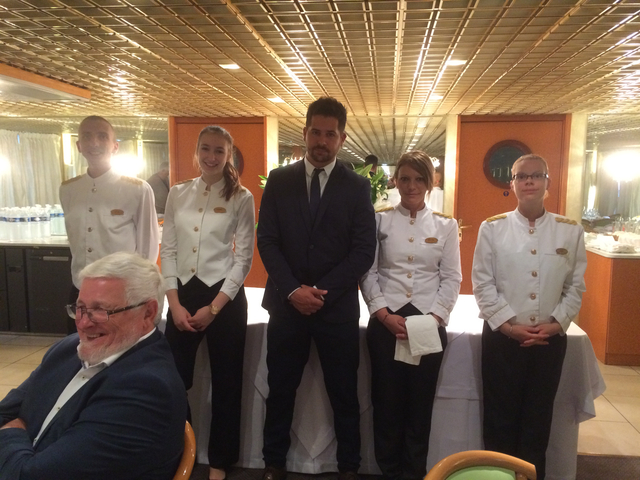 A group of crew members posing with a guest on a river cruise.
