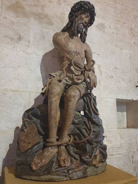       Statue of a bound figure in an indoor setting.
  