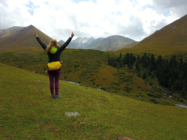       Hiker with arms raised in a mountainous landscape.
  