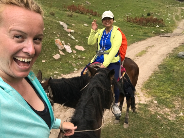       Two people on horses waving and smiling.
  