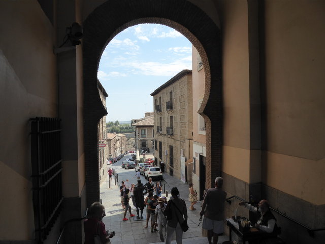 View through an archway onto a bustling street.