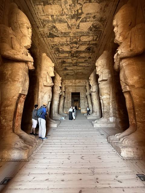       Interior corridor with large statues and ancient hieroglyphic reliefs.
  